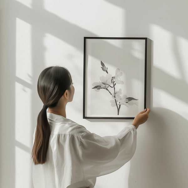Minimal black and white botanical wall art print being placed on a wall in a modern interior, clean and natural design