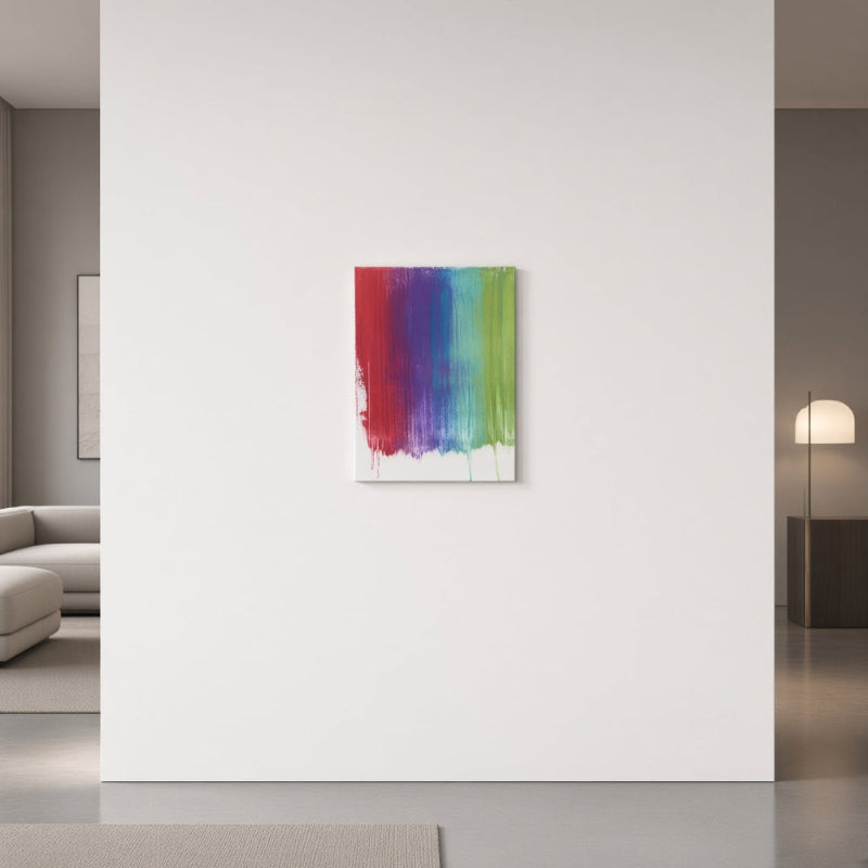 A vertical canvas wall art print featuring a vibrant rainbow brushstroke design, displayed on a minimalist white wall in a modern, softly lit living space.